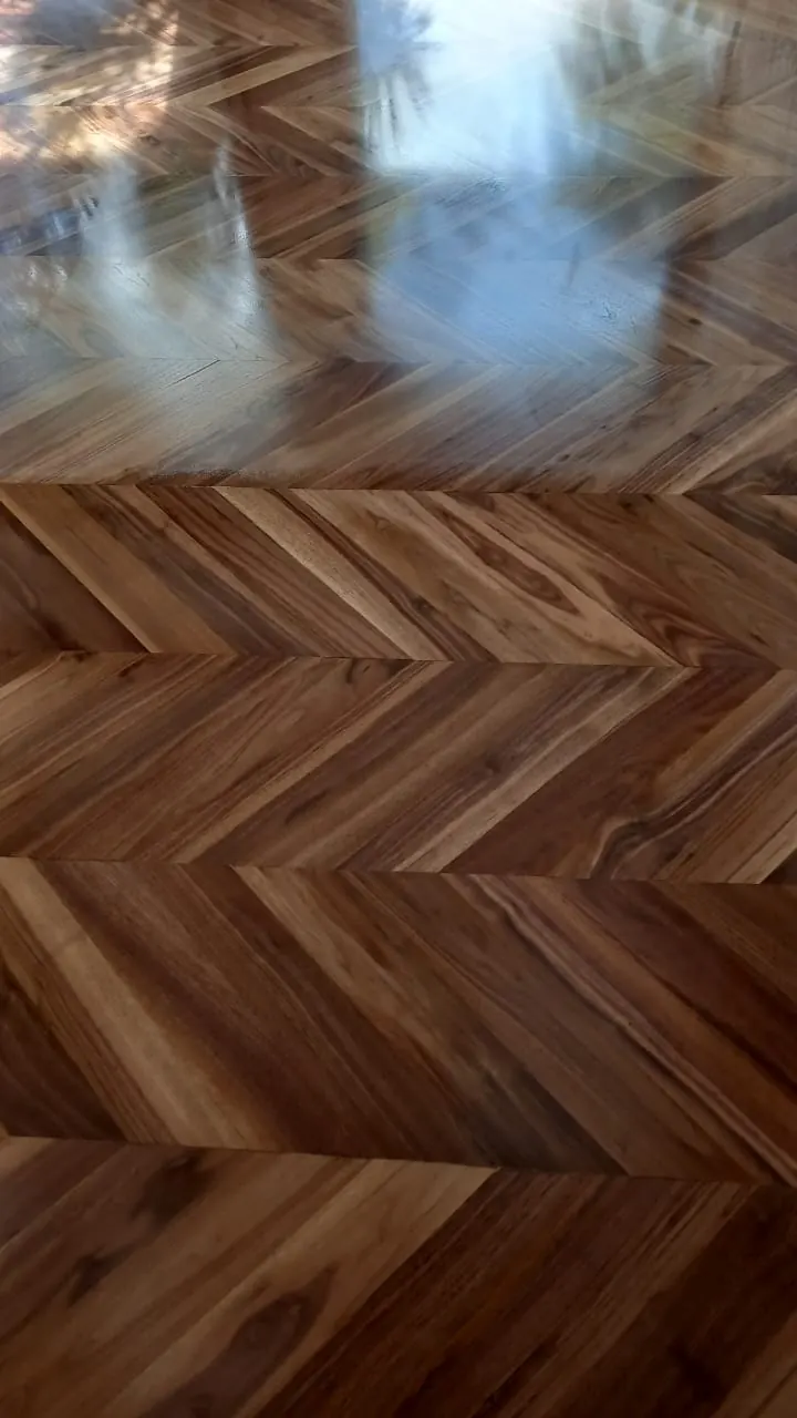 Parquet chevron, ou point de Hongrie, en bois brun vu de près : lames coupées en biais, veinage contrasté.