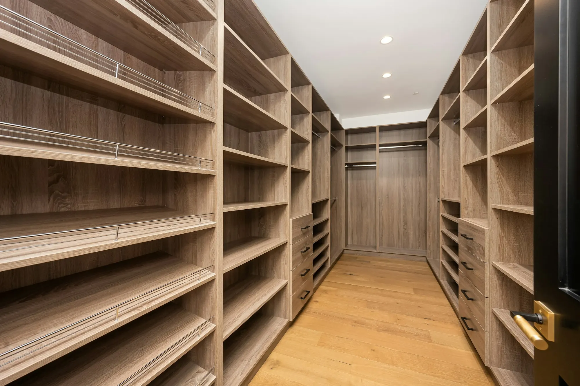 Dressing sur mesure en couloir : étagères en bois sur toute la hauteur, tiroirs et penderies, parquet clair.